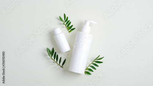 Clear cosmetic bottle containers and green leaves. Minimalist cosmetic product mockups. Natural hand care cream and lotion packaging, beauty SPA cosmetic branding concept