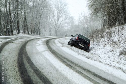 Abandoned car in the ditch the traffic accident during a snow fall. Symbolises bad weather conditions in winter, because of the black ice, snow or slush. 