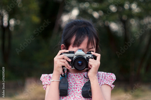 Portrait of asian cheerful little girl taking photo with film camera. © arrowsmith2