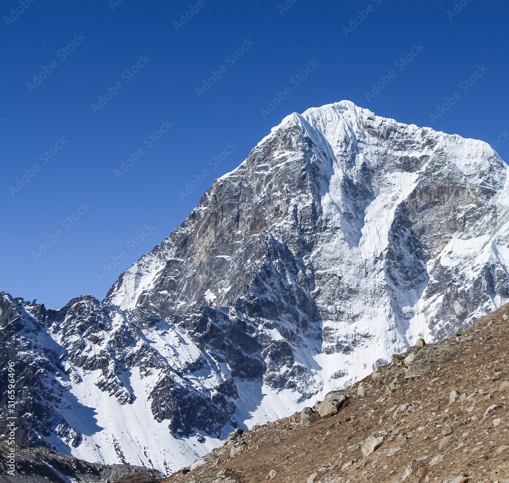 Taboche mountain peak in Himalayas in sunny day. It's a mountain in the Khumbu region of the Nepalese Himalaya. Route to Everest base camp in Sagarmatha national park.