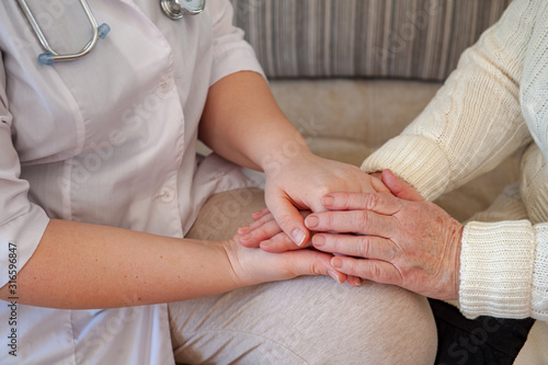 Pretty nurse in white coat helps sick retiree on social assistance program. Nurse carefully examines prescription of drugs, makes injections, measures blood pressure and cares.