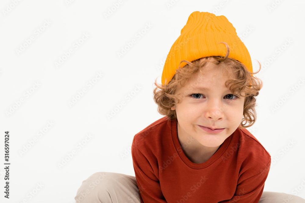 Portrait of charming boy with curly hair, yellow hat smiles isolated on white background Portrait of charming boy with curly hair, yellow hat smiles isolated on white background