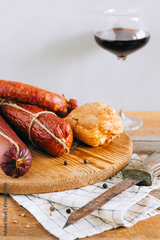 Assorted smoked sausages, appetizer to red wine on a wooden background