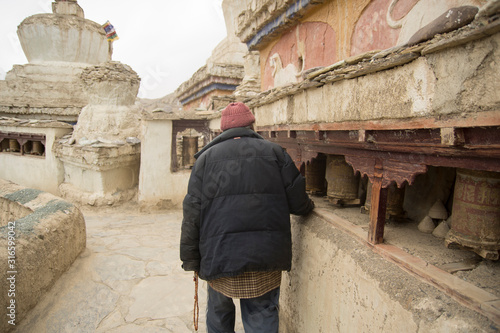 man spining prayer wheels in lamayuru monastery, ladakh, india © urdialex