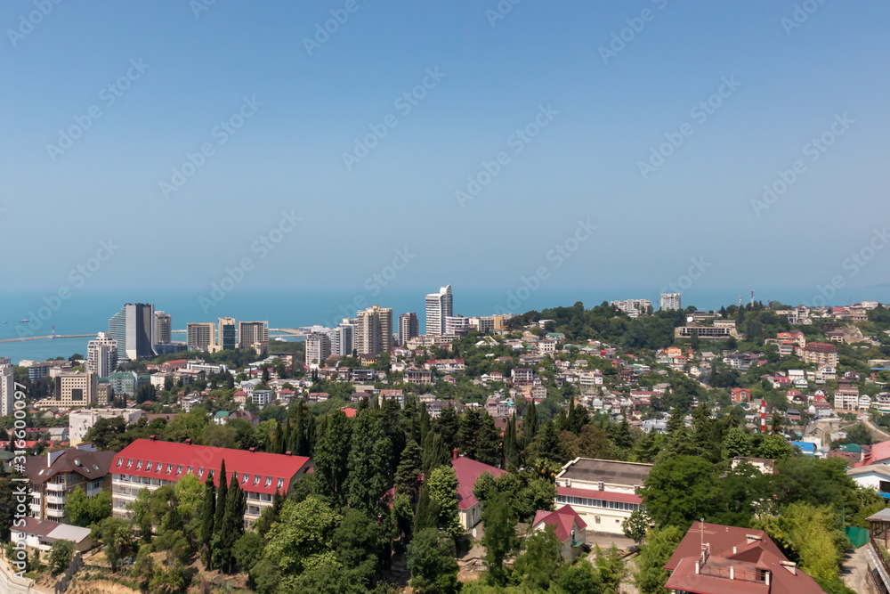 Blue coast of Black Sea in Sochi with houses and mountains, aerial panoramic view