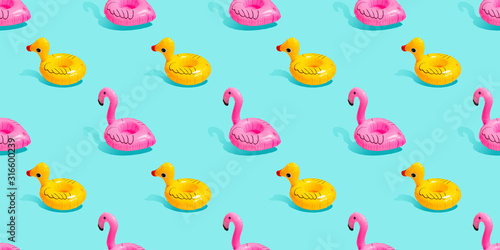 Obraz na plátně Top view colourful pink flamingo,yellow duck toys vibrant colors seamless pattern on light pastel blue background