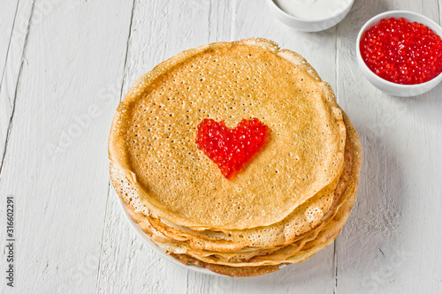 Stack of russian pancakes (crepes) with red caviar and sour cream. Traditional Maslenitsa (Shrovetide) meal.