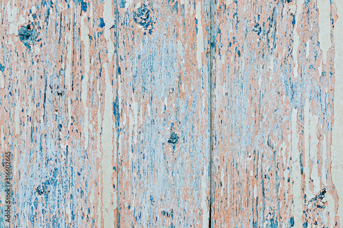 Flaking pink-blue paint on a faded wooden background