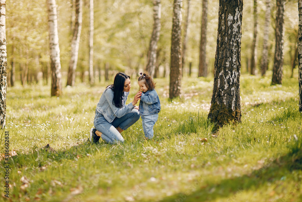 Beautiful mother with daughter. Family in a spring park. Woman in a blue jacket Beautiful mother with daughter. Family in a spring park. Woman in a blue jacket
