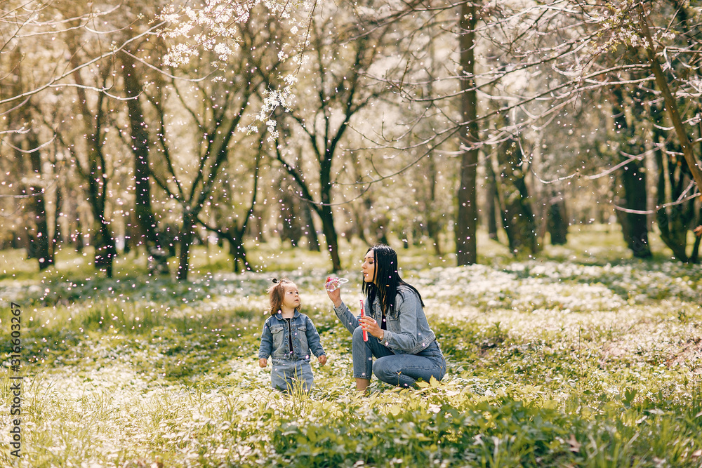 Beautiful mother with daughter. Family in a spring park. Woman in a blue jacket Beautiful mother with daughter. Family in a spring park. Woman in a blue jacket
