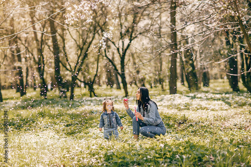 Beautiful mother with daughter. Family in a spring park. Woman in a blue jacket © hetmanstock2