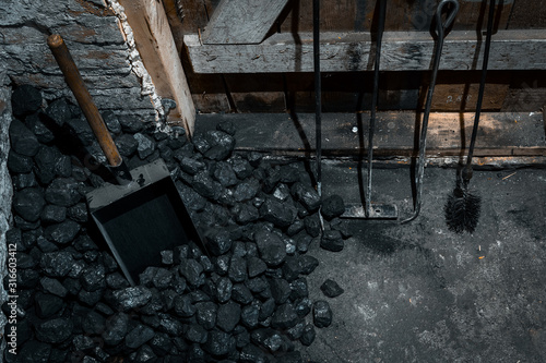 A coal shovel stuck in a pile of coalat the basement prepared for heating the house with.