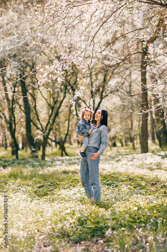 Beautiful mother with daughter. Family in a spring park. Woman in a blue jacket © hetmanstock2