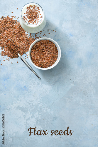 Bowl with flax seeds and glass of yogurt on color background