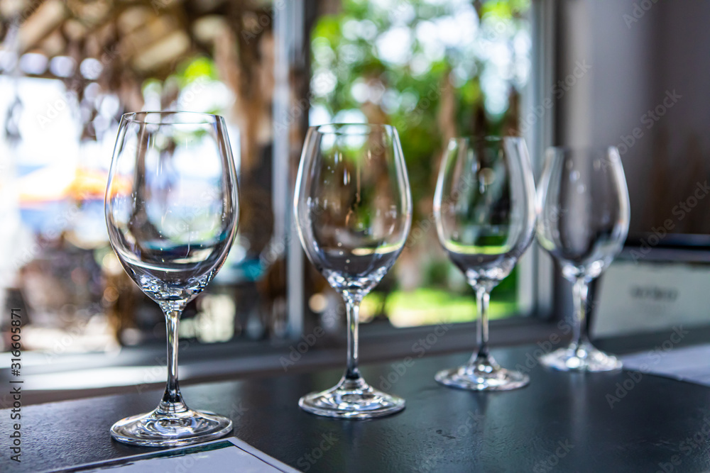 Side by side various sizes of wine empty glasses on a restaurant table selective focus view, goblets for drink and taste wines, tasting room stemware - obrazy, fototapety, plakaty 