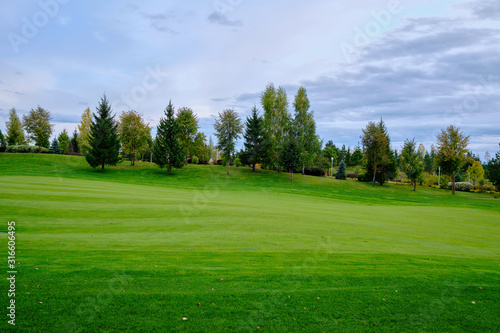 View of the golf course with green lawn trees and ornamental shrubs. Golf course, beautiful scenery.