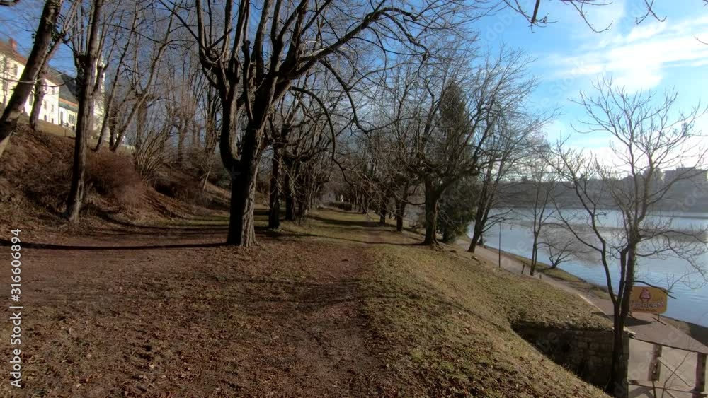 Forward dolly moving on pathway between old trees. On left side catholic church and on right side lake Bled, Slovenia Forward dolly moving on pathway between old trees. On left side catholic church and on right side lake Bled, Slovenia