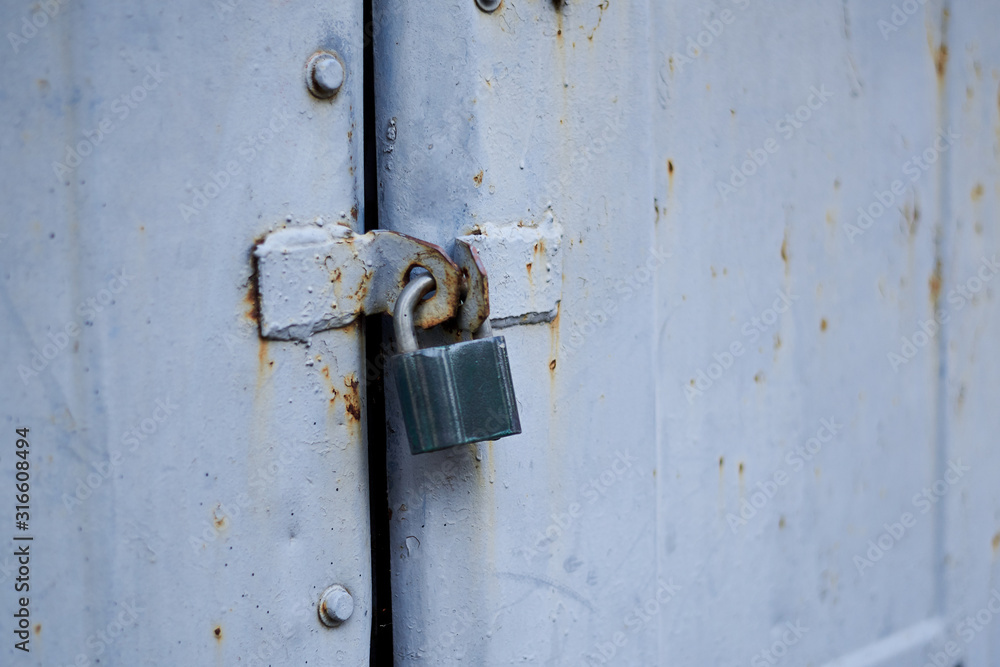 Old metal doors are closed on a padlock.