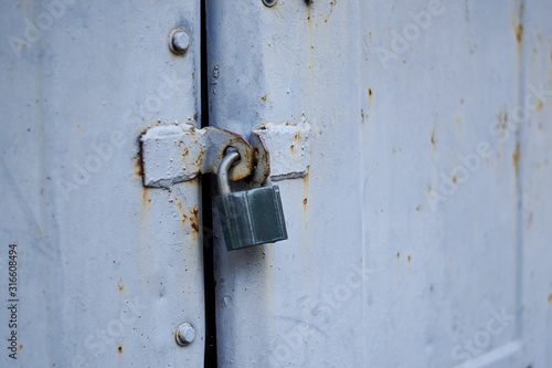 Old metal doors are closed on a padlock. © Konstiantyn Zapylaie