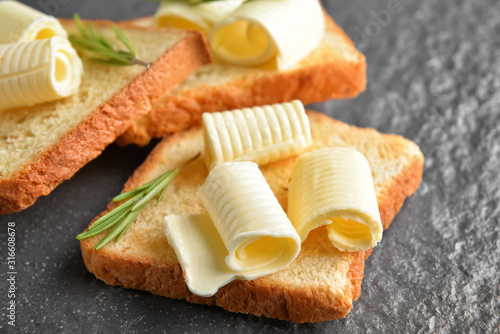 Toasted bread with butter and rosemary on dark background