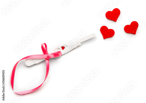 Pregnancy test and hearts on white background