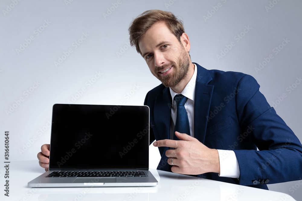 Confident businessman pointing to his laptop and smiling Confident businessman pointing to his laptop and smiling