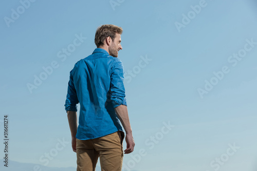 casual man standing relaxed with hands loose looking aside