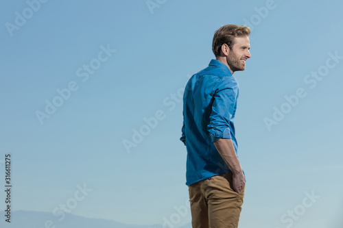 casual man standing with hands in pocket looking ahead happy