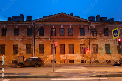 pedestrian crossing in front of an old house with showered plaster at dusk