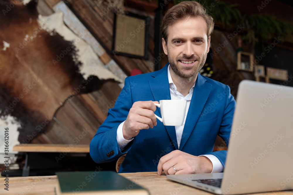 Positive businessman smiling and holding a cup of coffee Positive businessman smiling and holding a cup of coffee
