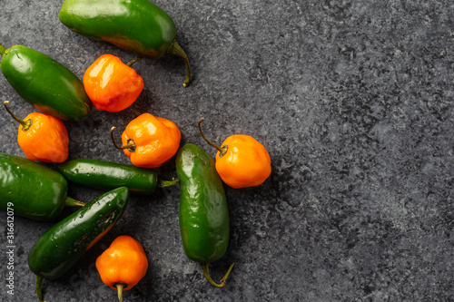 Fresh Picked Jalapeno and Habanero Peppers on dark concrete background