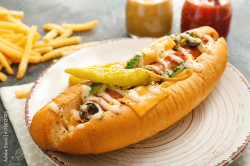 Plate with tasty hot dog on table