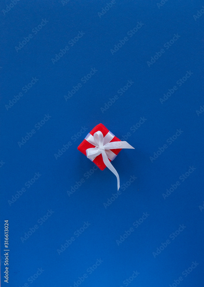 Valentines day composition. Flat lay with gift present red box, white ribbon on classic blue background. Top view, copy space, Greeting card. Valentine's day, birthday, wedding concept. Valentines day composition. Flat lay with gift present red box, white ribbon on classic blue background. Top view, copy space, Greeting card. Valentine's day, birthday, wedding concept.