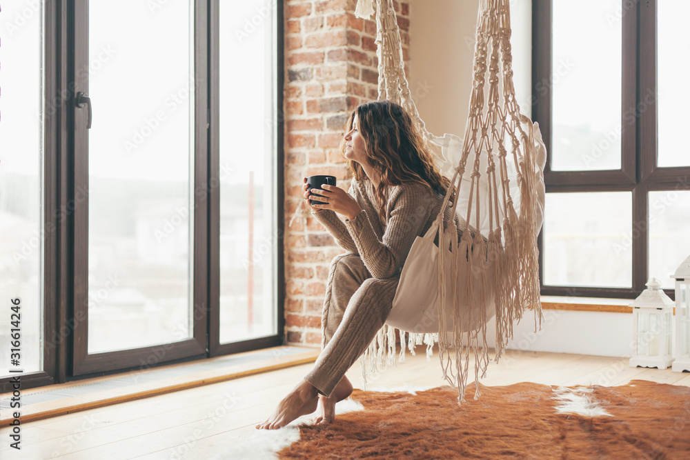 Woman wearing cashmere nightwear relaxing in cabin near fireplace - obrazy, fototapety, plakaty 