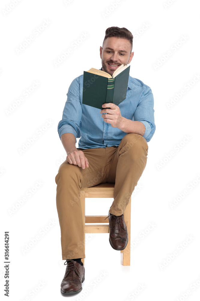 happy young man smiling and reading a book happy young man smiling and reading a book