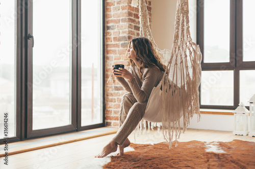 Woman wearing cashmere nightwear relaxing in cabin near fireplace