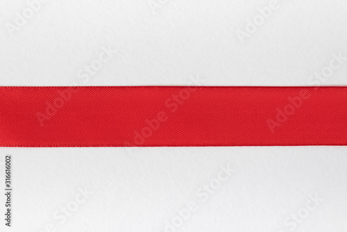 Horizontal red ribbon on a white background. Preparation for designer. Top view. Close-up