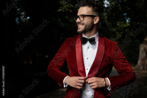 businessman fixing coat and looking aside with big smile photo