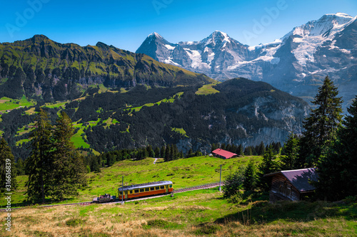 Electric tourist train and snowy Jungfrau mountains, Bernese Oberland, Switzerland