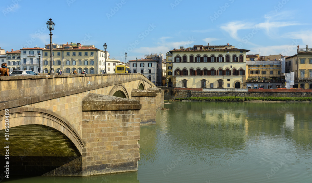 Arno River and the old promenade in Florence. Hazel houses with red roofs in Florence. Houses are reflected in the water.