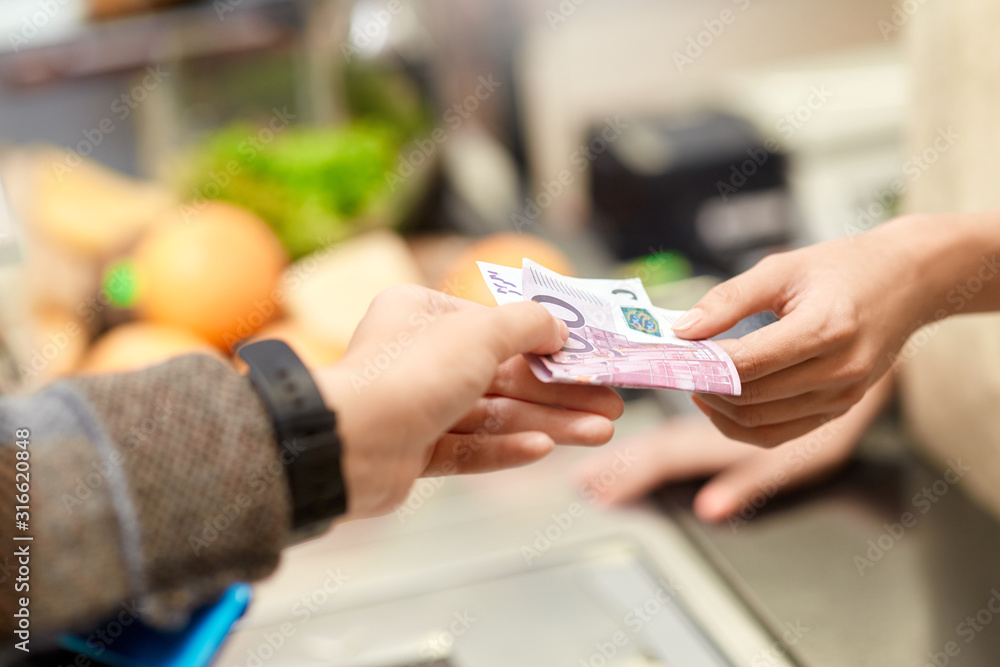 Young adult client and cashier holding money in hands Young adult client and cashier holding money in hands