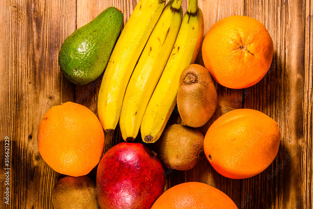 Still life with exotic fruits. Bananas, mango, oranges, avocado, grapefruit and kiwi fruits on wooden table. Top view Still life with exotic fruits. Bananas, mango, oranges, avocado, grapefruit and kiwi fruits on wooden table. Top view