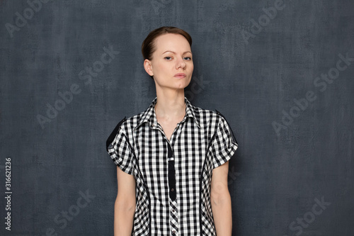 Portrait of focused self-confident young woman wearing checkered shirt © Andrei Korzhyts