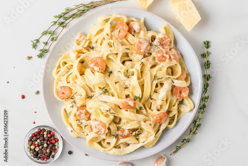 Pasta with shrimps, creamy sauce, parmesan cheese and thyme on a plate. Mediterranean fettuccine with seafood photo