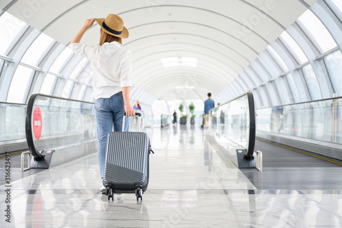 Photography A woman with hand luggage walking in airport terminal