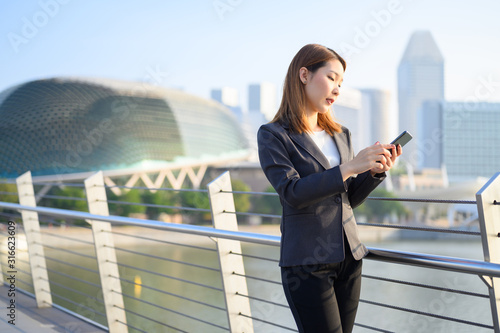 Photography Young Asian business woman with Phone standing outdoors using smartphone in modern city financial district