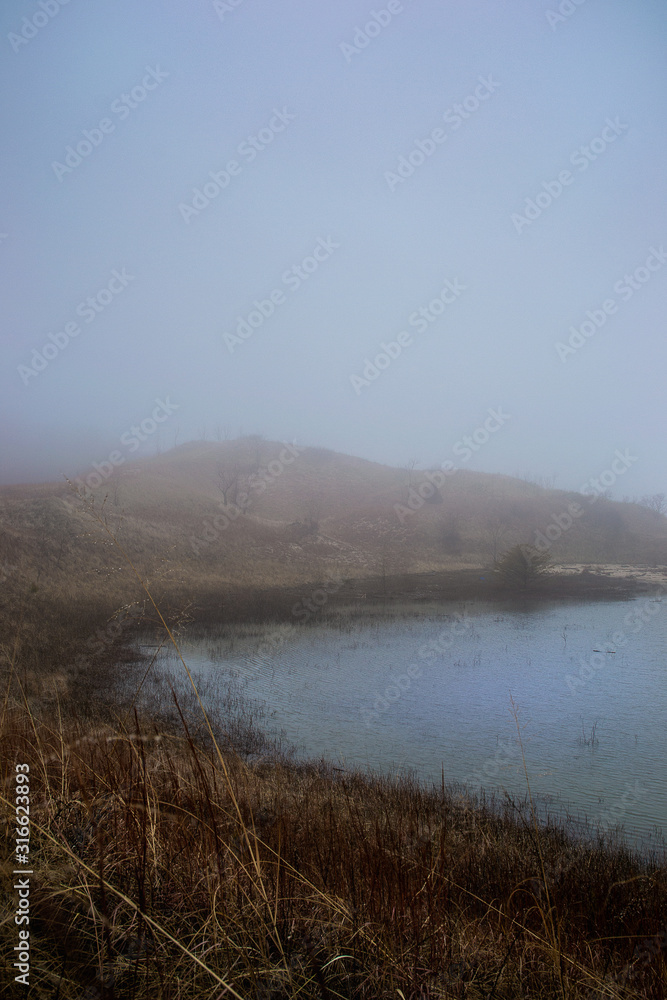 A foggy hillside above a serene lake A foggy hillside above a serene lake