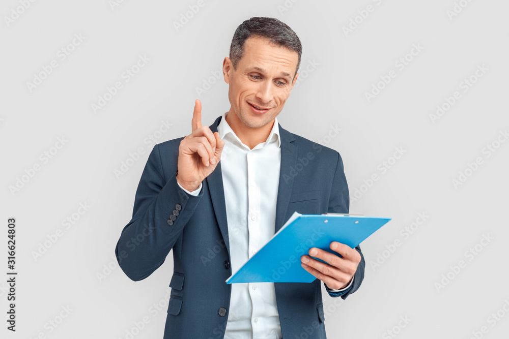 Freestyle. Mature businessman standing isolated on white with clipboard speaking pointing up idea smiling positive Freestyle. Mature businessman standing isolated on white with clipboard speaking pointing up idea smiling positive