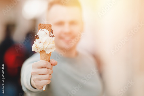 Happy male tourist holding italian ice cream in cone and smiling