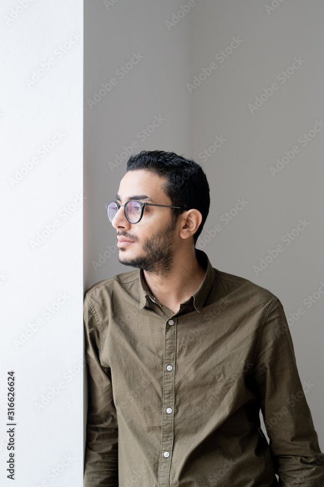 Obraz premium Serious or serene guy in eyeglasses looking through office window at break